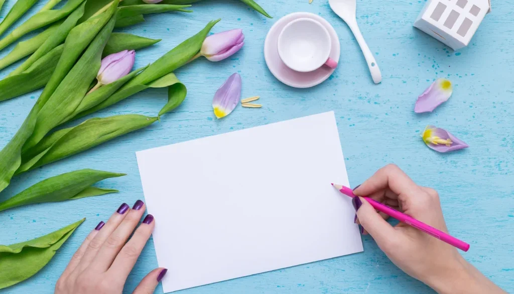 Kreatywne pisanie kartki na niebieskim tle z fioletowymi tulipanami i filiżanką kawy – pomysł na liścik z podziękowaniami