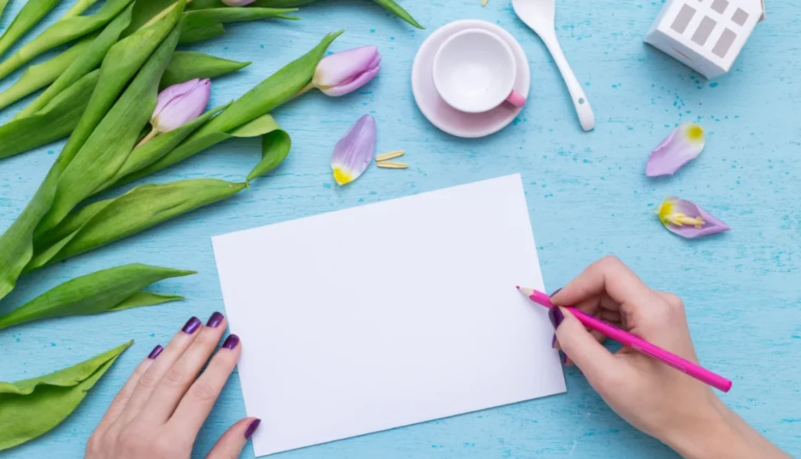 Kreatywne pisanie kartki na niebieskim tle z fioletowymi tulipanami i filiżanką kawy – pomysł na liścik z podziękowaniami