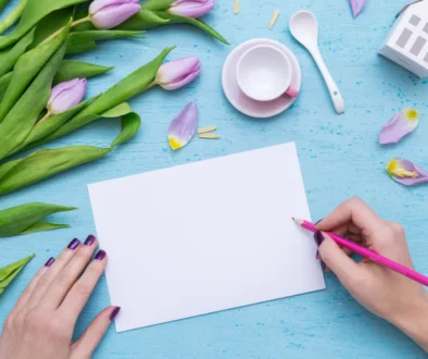 Kreatywne pisanie kartki na niebieskim tle z fioletowymi tulipanami i filiżanką kawy – pomysł na liścik z podziękowaniami